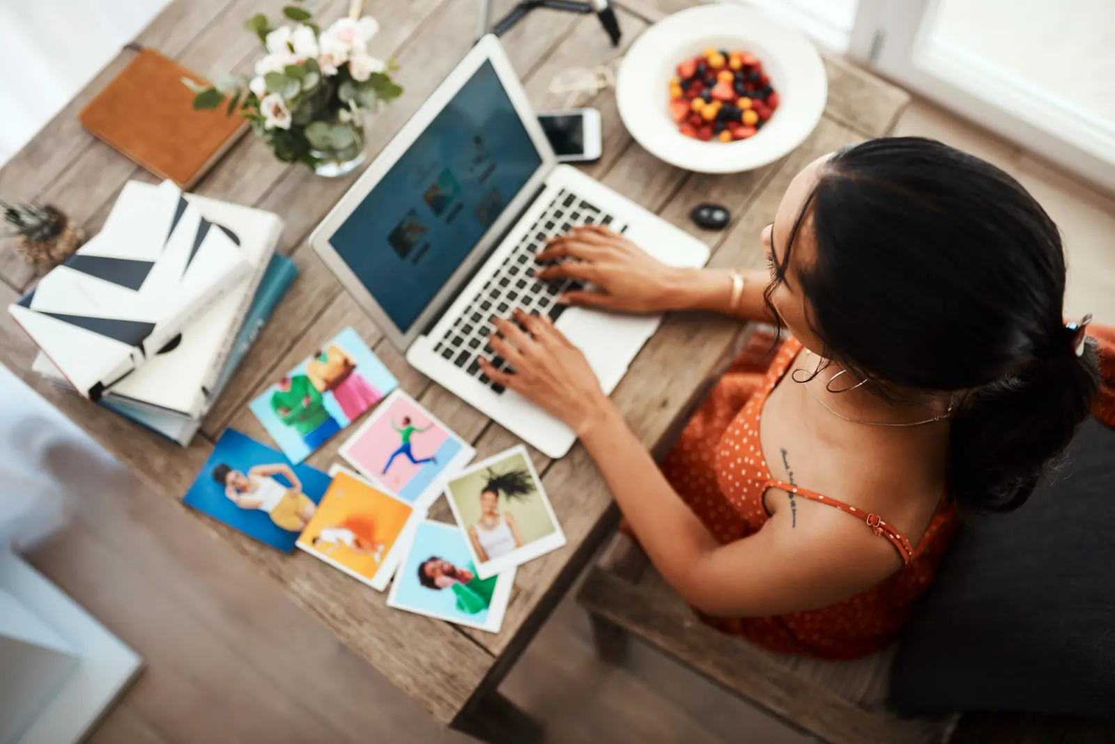 Someone reviewing site material at a laptop, with printouts spread across the desk