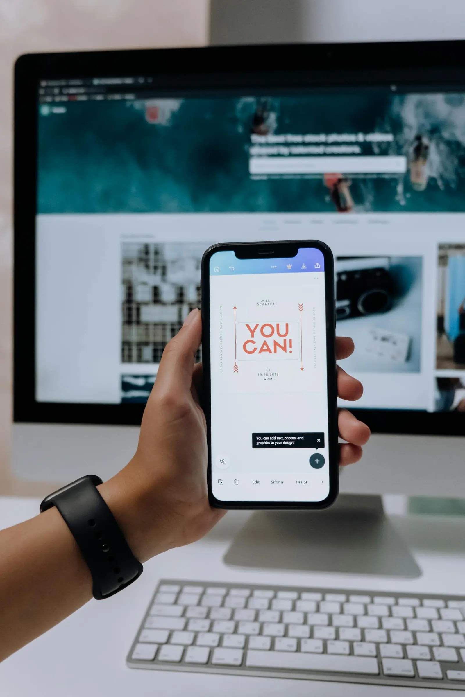 Hand holding smartphone with you can message in front of desktop screen