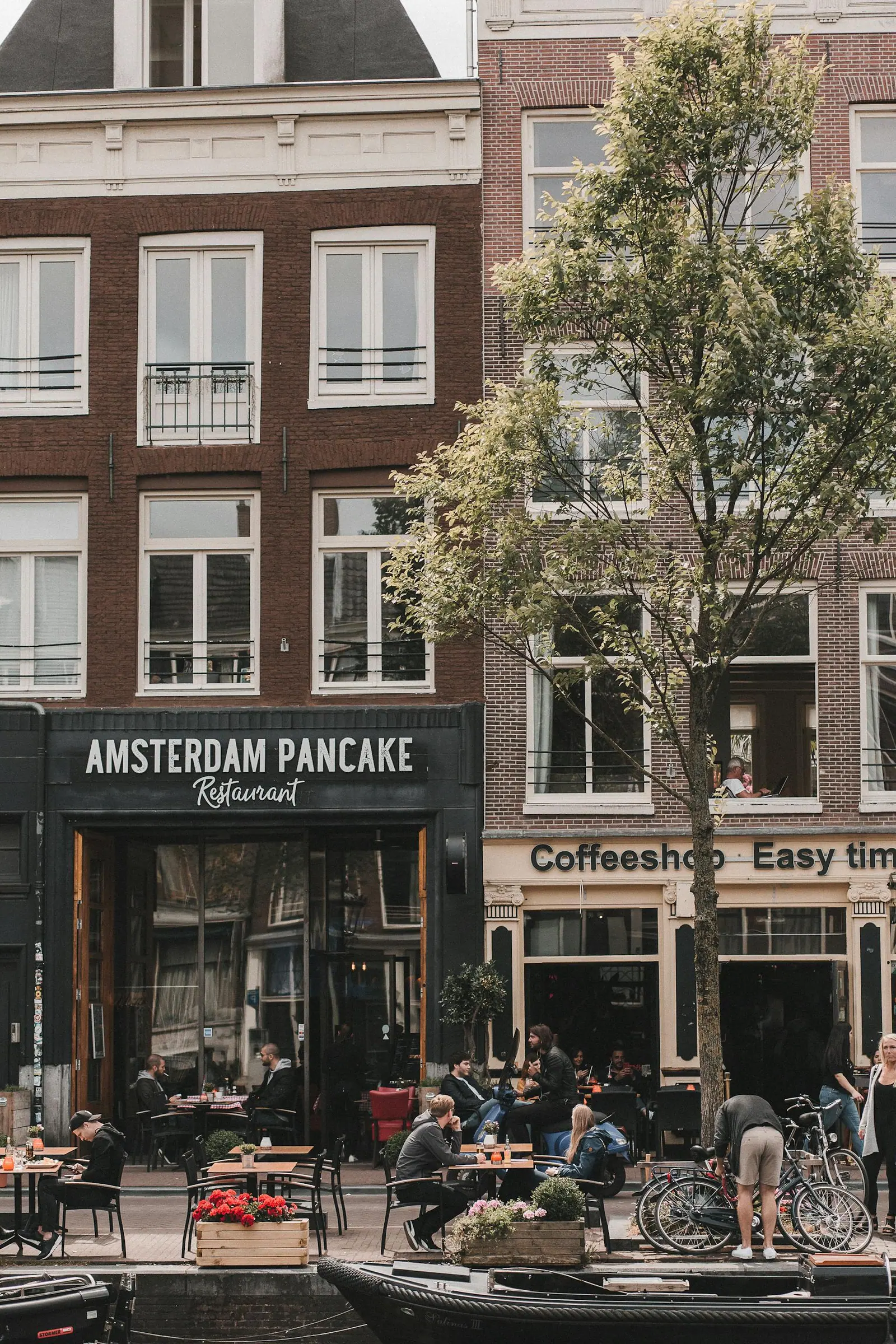 Charming daytime view of a lively amsterdam street with cafes and outdoor seating
