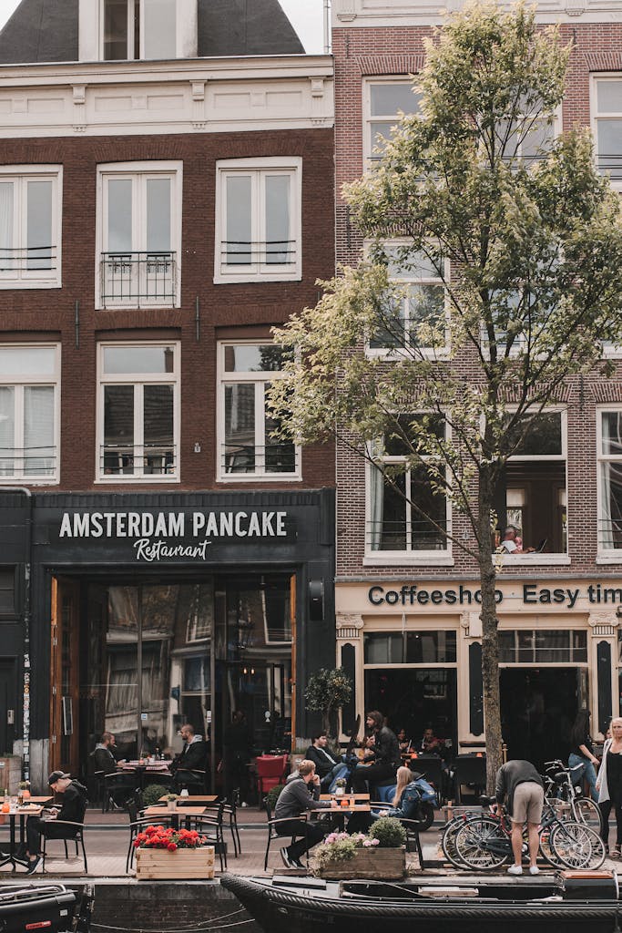 Charming daytime view of a lively Amsterdam street with cafes and outdoor seating.