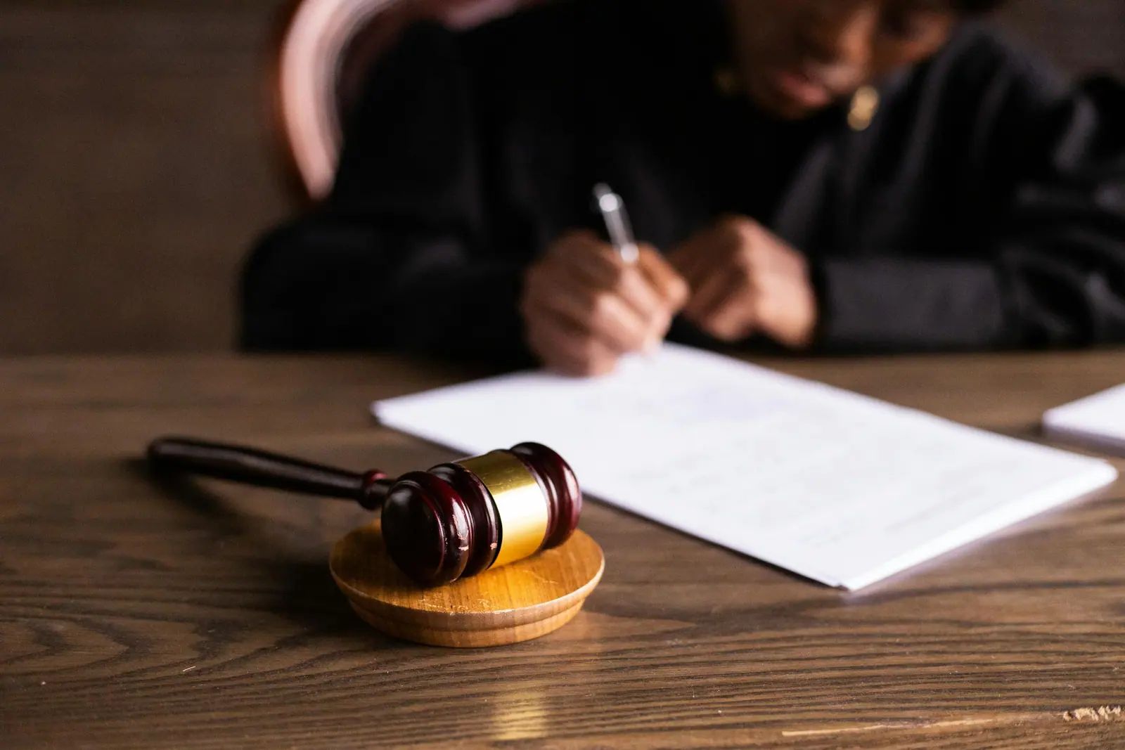 A judge signing documents at a desk, with a gavel in focus